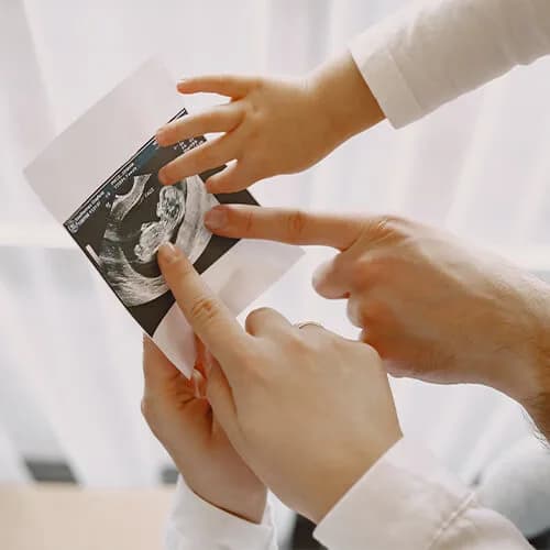 Parents and a small child holding an ultrasound scan photograph